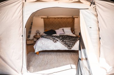 Battaniyeli ve yumuşak yastıklı bir çadırın parlak ve dostane odası rahat bir halının üzerinde - yaşam tarzı seyahat konsepti