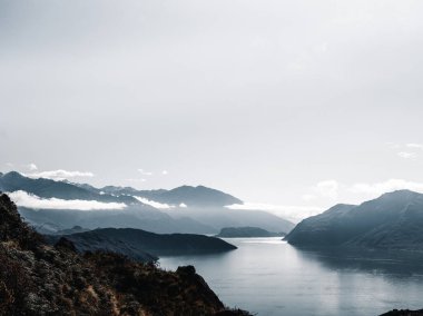 Gökyüzü biraz bulutlu güneşli ve parlak büyük mavi gölün manzarasını aydınlatan ve orman ağaçlarının yeşilliği arasında yüksek kayalık dağlar, Roys zirvesi, Yeni Zelanda - seyahat kavramı