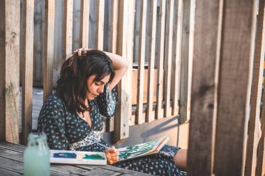 Genç ressam kız yerde oturup saçlarına dokunuyor - yaşam tarzı konsepti