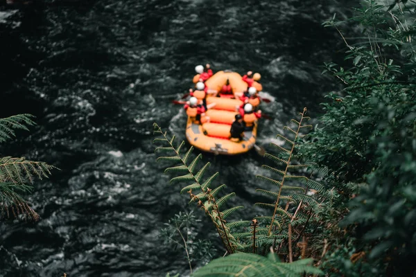Large inflatable boat with seven people on board rowing on the violent river with a lot of current among the vegetation in Okere, new zealand - Nature concept