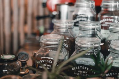 Farklı çay çeşitlerini içeren temiz cam kavanozlar hava geçirmez bir şekilde mühürlenmiş ve güzel bir kahve dükkanının parlak bir rafına yerleştirilmiş Mylk barı, Yeni Zelanda - yaşam tarzı konsepti