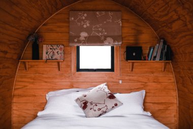 Küçük, parlak pencereli, kitap ve rahat yataklı rafların yanındaki ince kumaş perdelerle kaplı ahşap kabinin içi, te wepu podları akaroa, Yeni Zelanda -