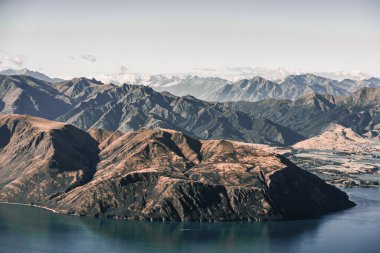 Büyük mavi gölün kıyısındaki büyük, etkileyici yüksek dağlar, sakin mavi sularında yol alan küçük bir tekne, birkaç bulutlu, Roys zirvesi, Yeni Zelanda - seyahat konsepti.