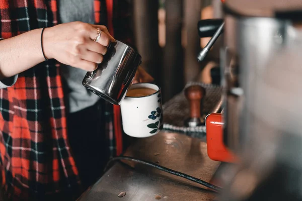 Genç Asyalı garson, kahve makinesinin yanında çiçekli bir bardak porselen ellerle zengin ve sıcak bir latte hazırlıyor, Mylk barı, Yeni Zelanda - yaşam tarzı konsepti