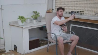 Genç erkek, kobayıyla selfie çekmek için akıllı telefon kullanıyor. Hayvan severler - 4K Yatay Video