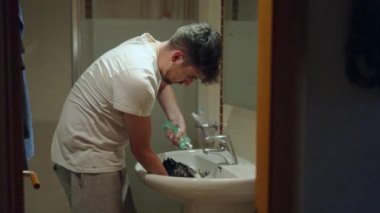 Genç adam denek domuzuna köpük banyosu yaptırmak için şampuan koyuyor - orta boy - 4K yatay görüntü