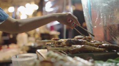 Tanımlanamayan bir kadın gece pazarında et broşürlerini çeviriyor. 4K yatay video.