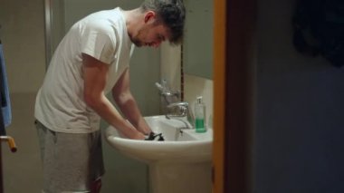 Genç beyaz adam lavabodaki kobay hayvanını temizlemek için şampuan kullanıyor. 4K Yatay Video.