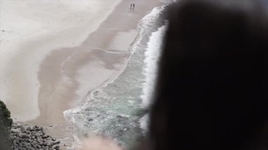 Yeni ahbaplar plajına, yeni Zelanda 'ya tepeden bakan taraçada oturan tanınmayan bir kadın.