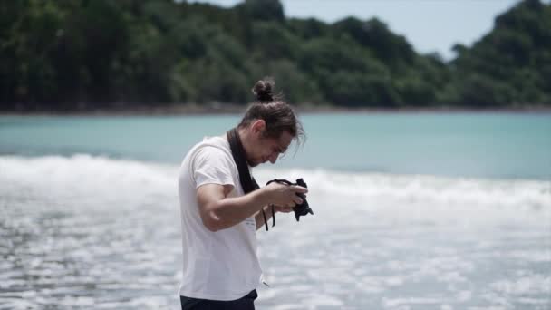男の写真家はビーチでカメラを見て新しいチャムビーチ ニュージーランド 水平ビデオ — ストック動画