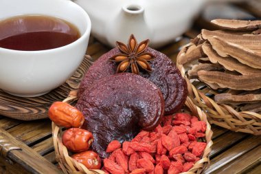Reishi veya lingzhi mantarı, goji üzümü, kırmızı jube ve çay doğa arka planında.