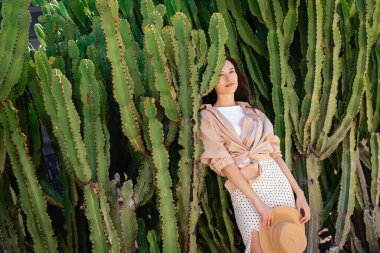 woman in shirt and skirt standing near green giant cactuses