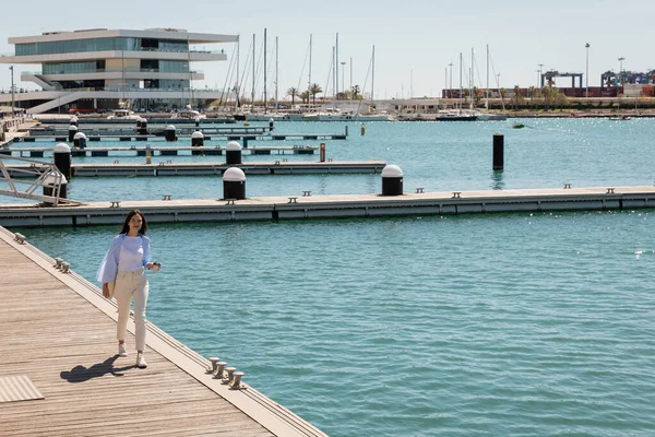Kahveli esmer bir kadının rıhtımda yürümesini uzun süre izlemek.