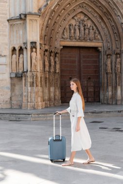Valencia 'da valiziyle yürüyen kızıl saçlı genç bir kadın.