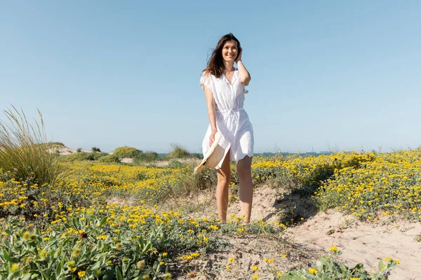 Mulher Positiva Vestido Verão Branco Segurando Chapéu Palha Praia — Fotografia de Stock