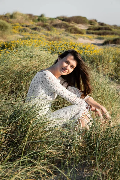 Kumsalda Çimenlerde Otururken Kameraya Bakan Örgü Elbiseli Güzel Esmer Kadın — Stok fotoğraf