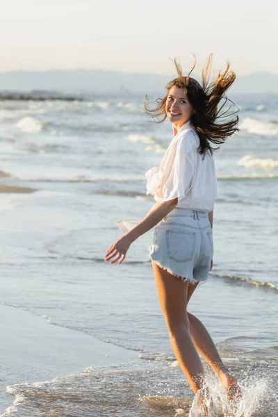 正の女性でシャツ見ますカメラで海の海岸 — ストック写真