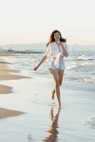 幸せな若いです女性ランニング上のぬれた砂の上に海の海岸 — ストック写真