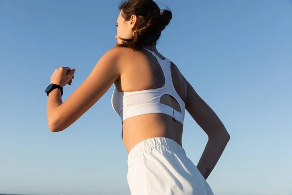 夏に青空に向かってジョギングする若いスポーツ女性の低角度ビュー — ストック写真