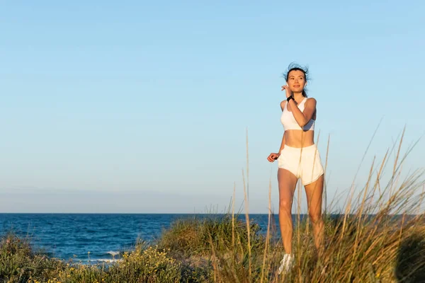 Young Woman Shorts Wireless Earphones Jogging Grass Sea Shore — Stock Photo, Image