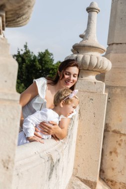 Mother and toddler daughter standing on stone Puente Del Mar bridge in Valencia
