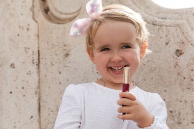 Gülümseyen bebek Valencia 'da dudak parlatıcısı tutuyor.