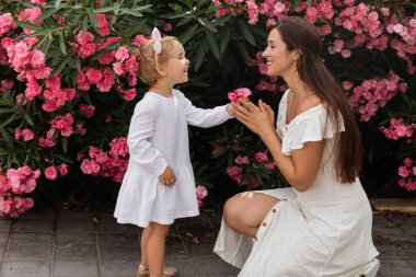Valencia 'da annesine çiçek veren, yaz elbisesi içinde gülümseyen küçük kızın yan görüntüsü.