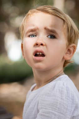 Portrait of sad toddler girl looking away outdoors 
