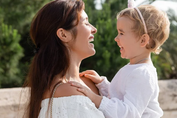 Valencia 'da annesiyle gülen küçük kızın yan görüntüsü.