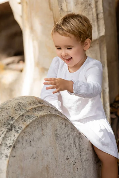 Happy Toddler Kid White Dress Sitting Stone Bench Park Spain — Zdjęcie stockowe