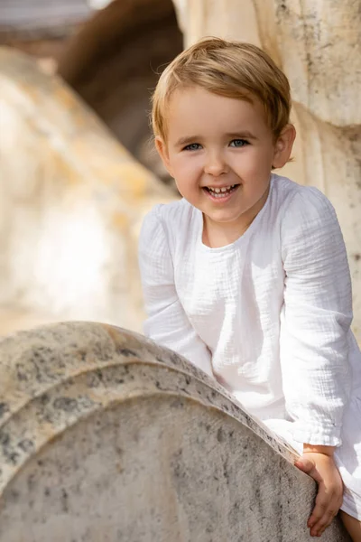 Χαμογελαστό Κοριτσάκι Λευκό Φόρεμα Κάθεται Πέτρινο Παγκάκι Στο Πάρκο — Φωτογραφία Αρχείου