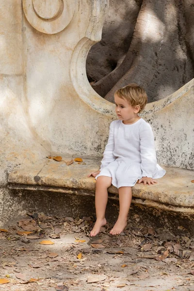 Ξυπόλητο Κοριτσάκι Φόρεμα Κάθεται Πέτρινο Παγκάκι Στο Πάρκο Στη Βαλένθια — Φωτογραφία Αρχείου