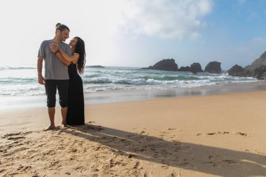 Portekiz 'de okyanus kenarında, uzun boylu, dövmeli, neşeli erkek arkadaşı olan bir kadın.