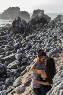 Portekiz 'de Rocky Beach' te sakallı adama sarılan dövmeli bir kadın. 