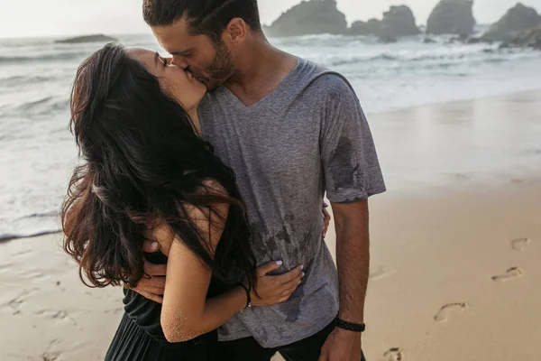 穿着灰色T恤的大胡子男人在靠近大海的地方亲吻女朋友 — 图库照片