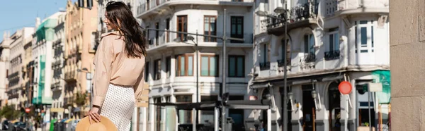 Back view of brunette woman in beige shirt on urban street, banner - foto de stock