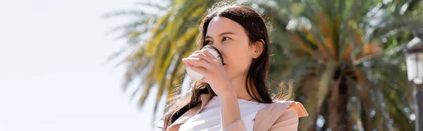 Low angle view of brunette woman drinking coffee outdoors, banner — Photo de stock