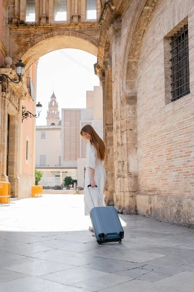 Улыбающаяся рыжеволосая женщина в полный рост прогуливается с рюкзаком по улице Валенсии — стоковое фото