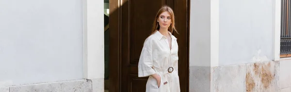 Volle Länge der jungen rothaarige Frau in Kleid, die mit der Hand in der Tasche auf der Straße in Valencia geht, Banner — Stockfoto