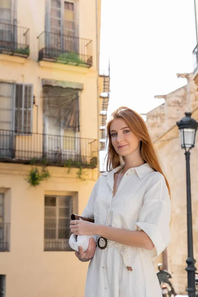 Усміхнена молода жінка в одязі тримає гаманець на вулиці Валенсії — стокове фото
