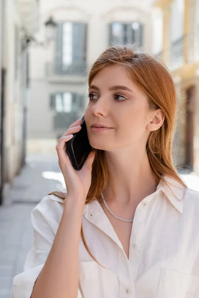 Портрет рыжеволосой женщины, говорящей на смартфоне и смотрящей в Валенсию — стоковое фото