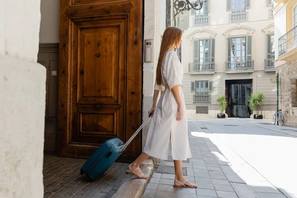 Comprimento total da jovem no vestido andando com bagagem na rua europeia — Fotografia de Stock