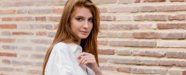 Retrato de ruiva mulher em vestido posando perto da parede de tijolo na rua europeia, banner — Fotografia de Stock