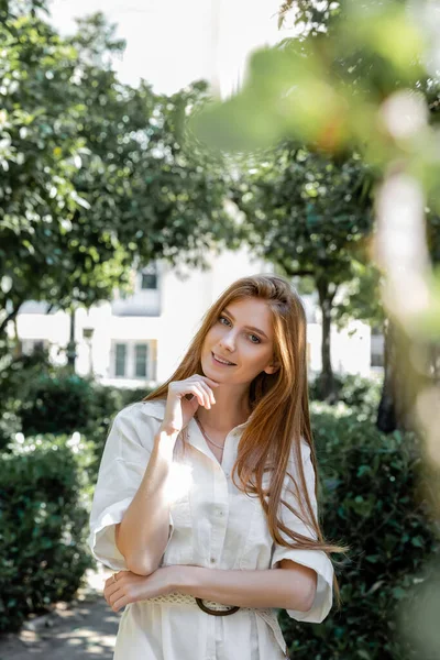 Portrait of pleased and redhead woman in dress looking at camera in green park in valencia — Stock Photo