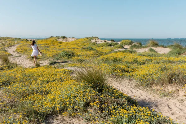 Rückansicht einer Frau mit Sonnenhut, die am Strand läuft — Stockfoto