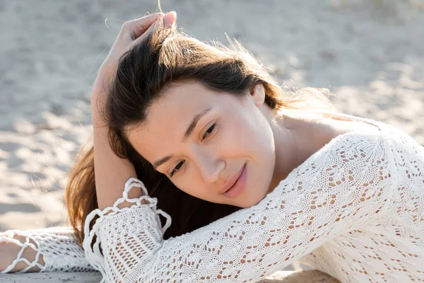 Ritratto di giovane donna in abito bianco lavorato a maglia che distoglie lo sguardo sulla spiaggia sfocata — Foto stock