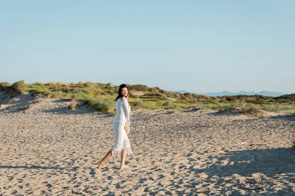 Glückliche Frau mit Strohhut und Blick in die Kamera am Strand — Stockfoto