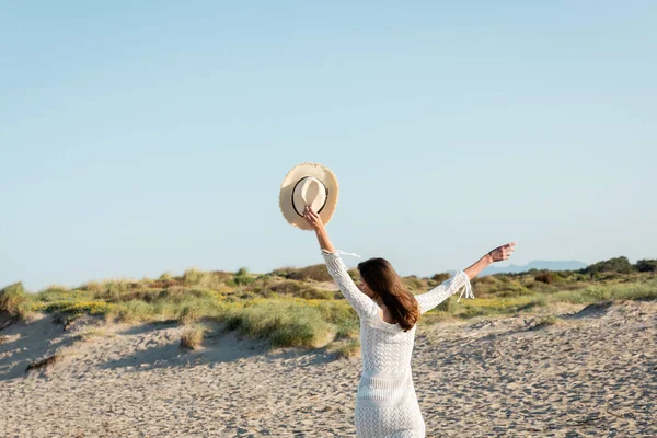 Молодая женщина держит шляпу солнца во время бега по пляжу — стоковое фото