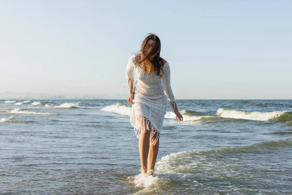 Morena mujer en vestido de pie en agua de mar - foto de stock