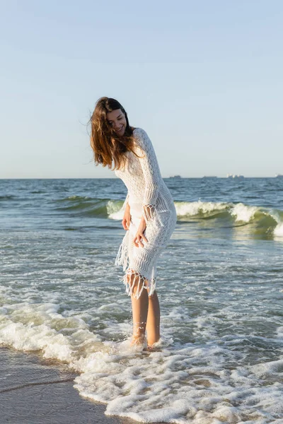 Mulher feliz em vestido de pé na água do mar na praia — Fotografia de Stock